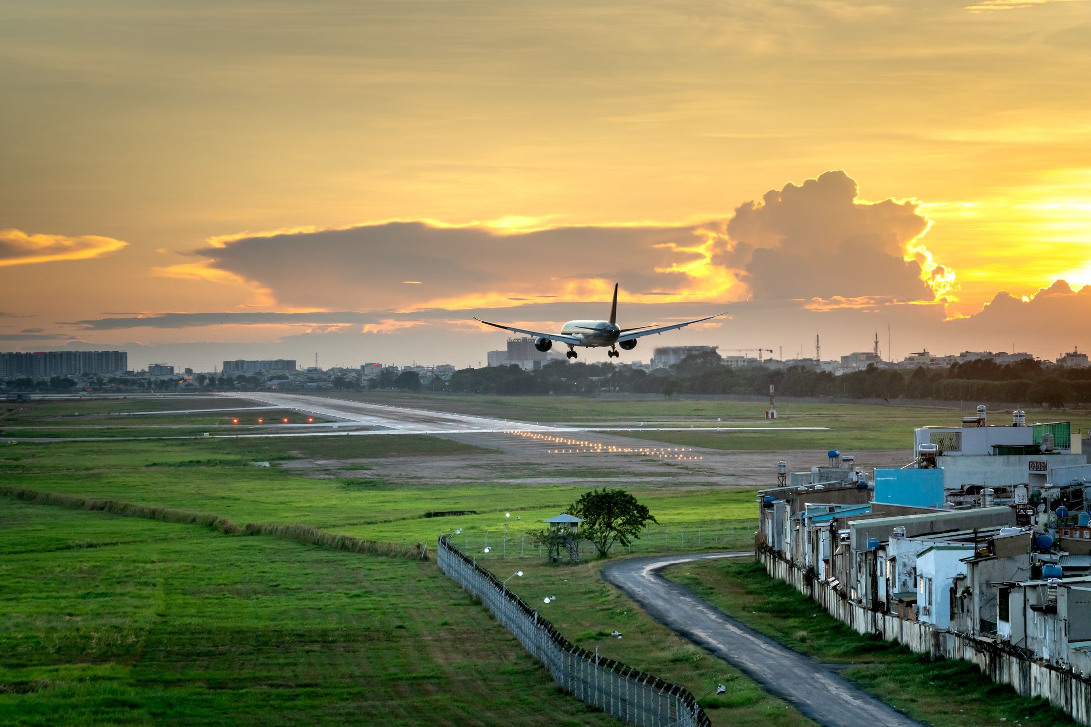 Passenger aircraft on final approach at sunset over an airport runway